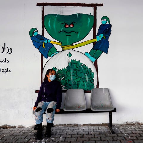 A Palestinian child sits beneath graffiti depictin
