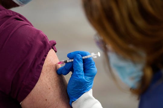 A health care worker receives a second Pfizer-BioNTech COVID-19 vaccine shot at Beaumont Health in Southfield, Tuesday, Jan. 5, 2021.