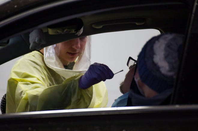 An Avera Health worker provides a COVID-19 test to a citizen on Wednesday, January 6, at a testing site set up in a former car dealership in Sioux Falls.