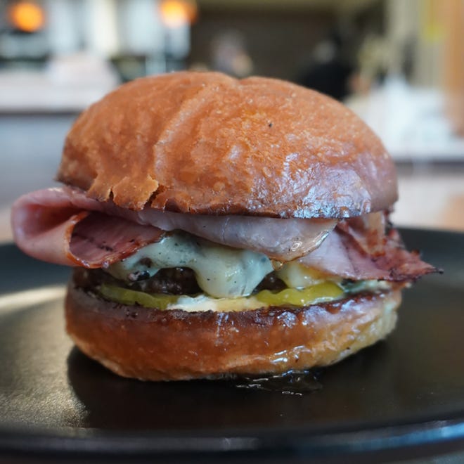 The Triple H burger is an oak-grilled burger patty finished with truffle dijon aioli, hot honey, ham, pickles and havardi cheese.