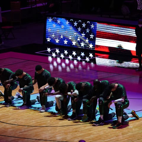 Celtics players kneel during the playing of the na