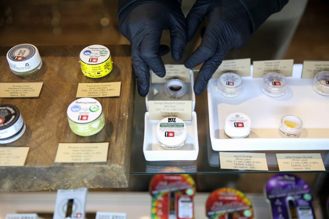 A bud tender straightens recreational marijuana products at Tokyo Starfish Recreational Marijuana in Salem. Oregon's recreational marijuana sales topped $1 billion during 2020.