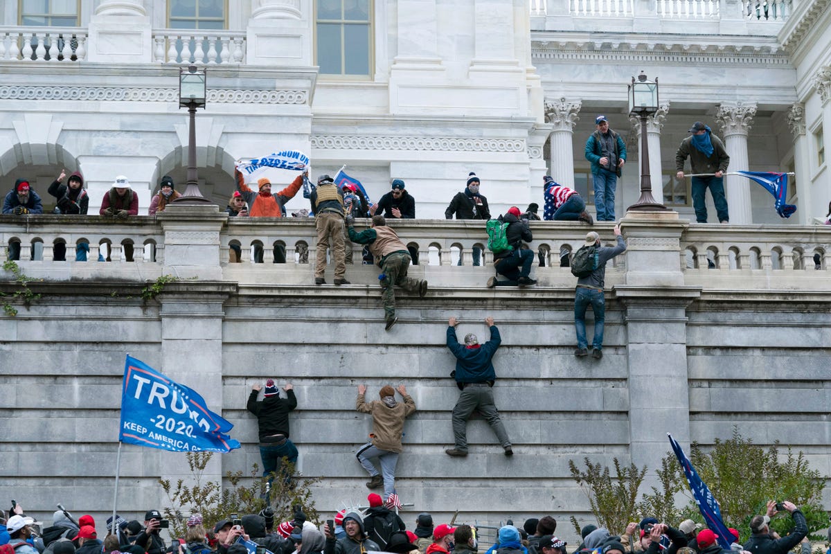 Rioting supporters of President Donald Trump climb the west wall of the the U.S. Capitol in Washington.