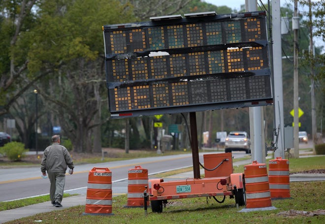 A pedestrian walks down the sidewalk on Hartley Road past a sign announcing COVID-19 testing at the Mandarin Senior Center site in January. The center is holding a make-up date for residents who received an initial dose of the two-dose vaccine but not a second dose.
