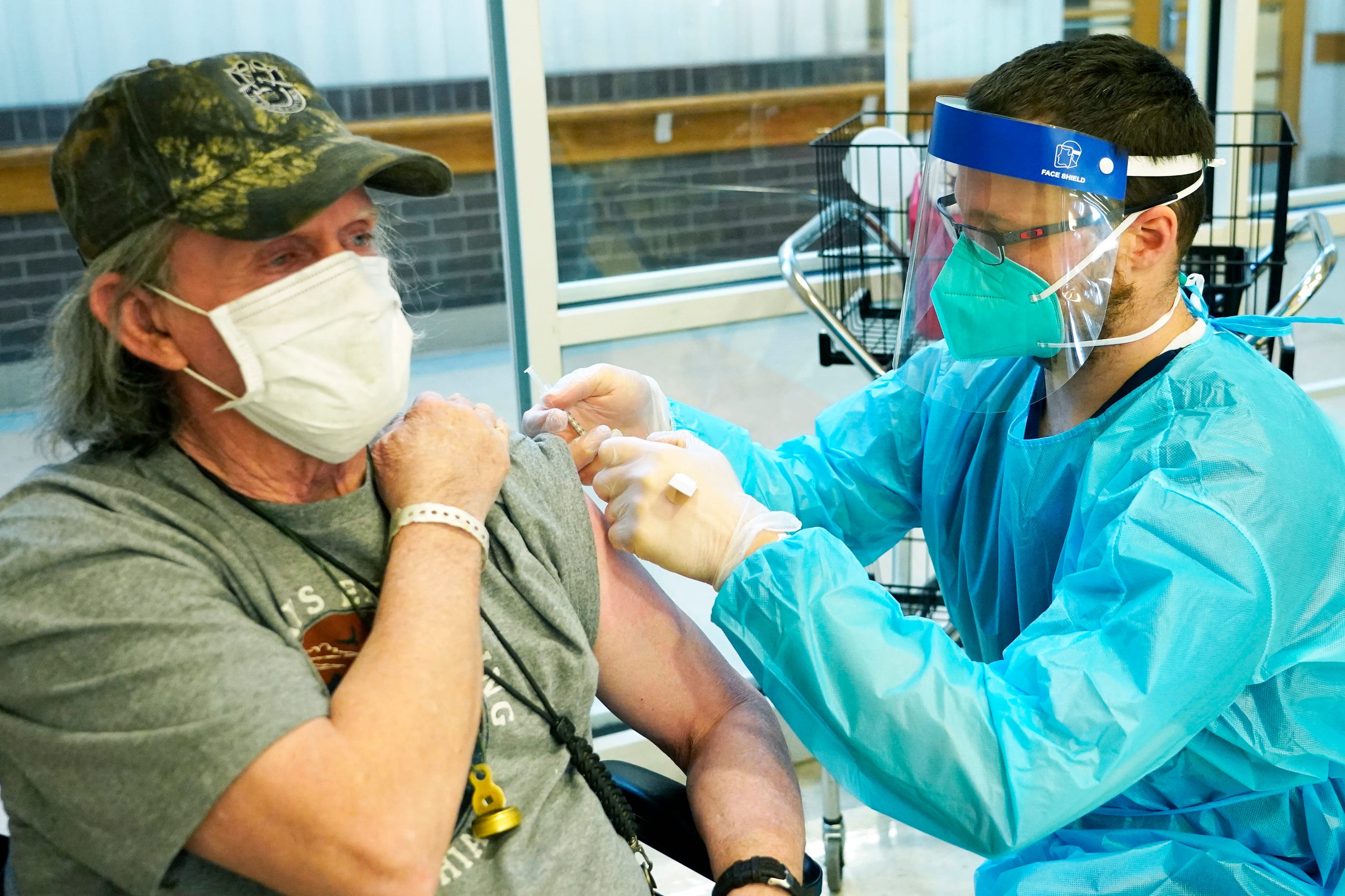 James Hill, 69, who served separate stints in both the Army and Navy, left, holds his sleeve as Brent Myers, a CVS pharmacist, readies to administer the Pfizer COVID-19 vaccination, at the Mississippi State Veterans Home in Jackson, Miss., Jan. 9, 2021. Hill was among the first residents to receive the Pfizer covid vaccination. Residents and staff at two of the four veterans homes were inoculated on Saturday with the vaccinations planned for the two other homes next week. The veterans homes were among the hardest hit senior living facilities by the virus.