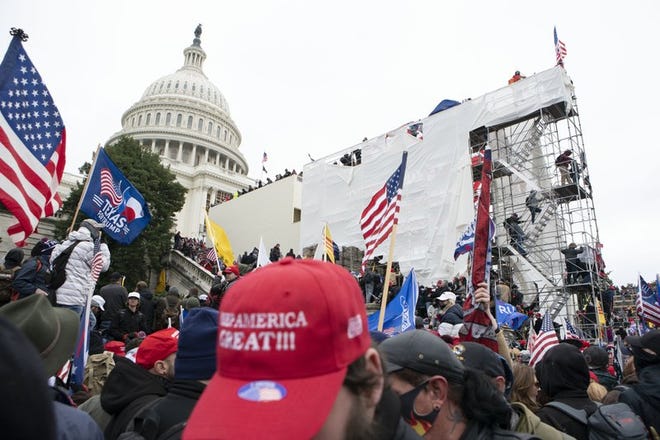 Supporters of President Donald Trump climb on an inauguration platform on the West Front of the U.S. Capitol on Wednesday, Jan. 6, 2021, in Washington.