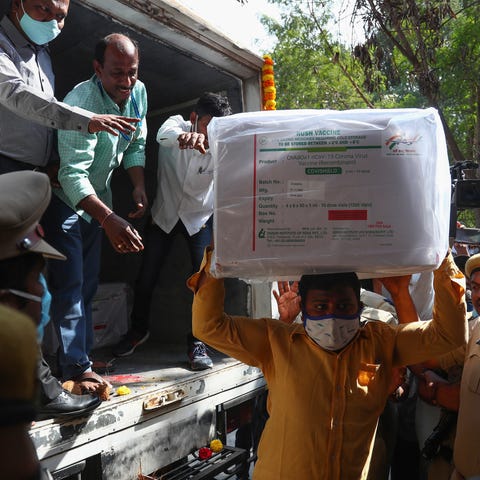 Health workers shift a box containing COVID-19 vac