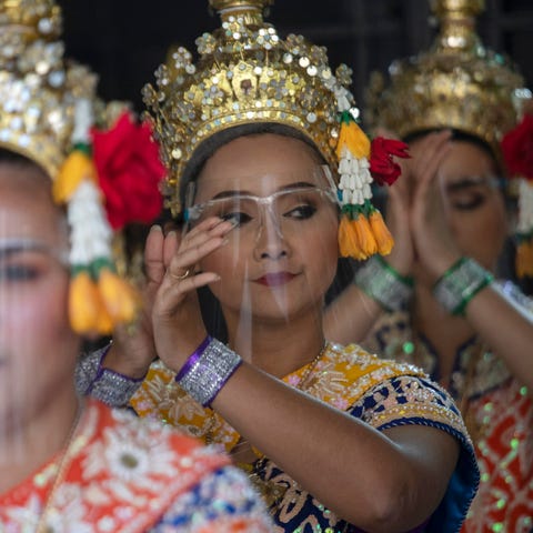 Thai classical dancers wearing face shields to hel