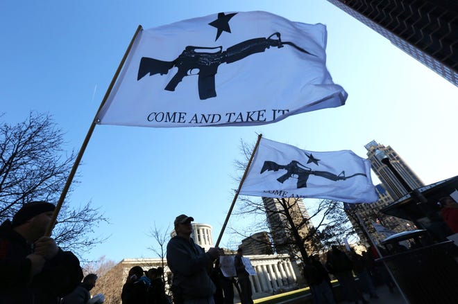 Jamie Sears and John Burrows, both friends from Galloway, hold flags imploring, "Come and Take It" during a rally organized by the group Guns Across America on the Ohio Statehouse Lawn in Columbus, Ohio.