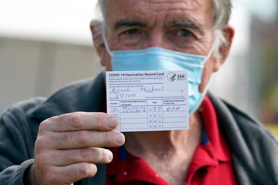 Dr. Michael Roach shows his vaccination card on Wednesday after receiving the Moderna COVID-19 vaccine at a site for health care workers in Pacoima, Calif.