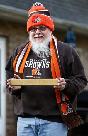 Ralph Mausser has had Cleveland Browns season tickets since 1969. He grew up in Cleveland and moved to Delaware County for work in 1990, but went to every home game for years. He canceled his season tickets this year because of the pandemic but was still watching at home. He was photographed in his home with a slat from his old seat in the city stadium on Thursday, January 14, 2021.