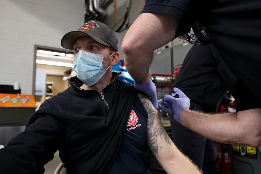 Whitman firefighter and paramedic Russell Lucas is given his first dose of the Moderna COVID-19 vaccine at the Whitman Fire Department headquarters in Massachusetts on Thursday, Jan. 14, 2021.