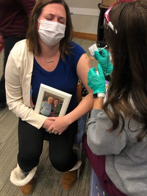 Mia Hurley, 29, holds a photo of herself with her grandmother, Sue Hurley, on Dec. 30, 2020, at a COVID-19 vaccine clinic for healthcare workers at Cincinnati Children's Hospital Medical Center. Mia Hurley is a nurse there. Her grandmother died from COVID-19 the day before, on Dec. 29, 2020.