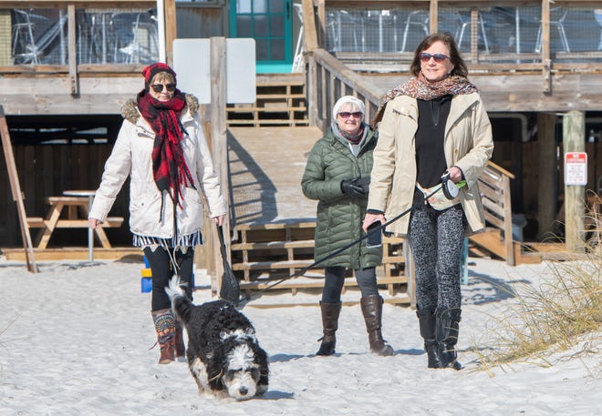 Joyce Decker, of Traverse City, Michigan, right, walks her dog Zoey, along with her sisters Jill Sullivan, left, and Janis Jankowski at Navarre Beach on Wednesday, Jan. 13, 2021.