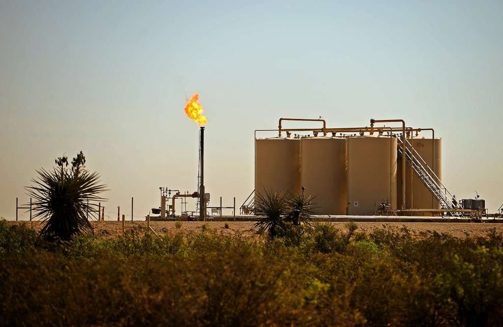 A natural gas flare burns near storage tanks in Reeves County in West Texas.