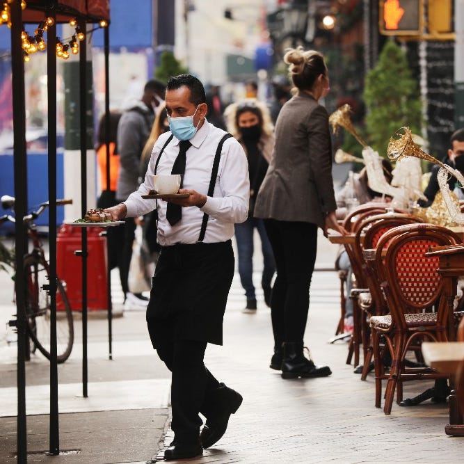 A waiter moves between tables outside of a restaurant in Manhattan on Dec. 11 in New York City.