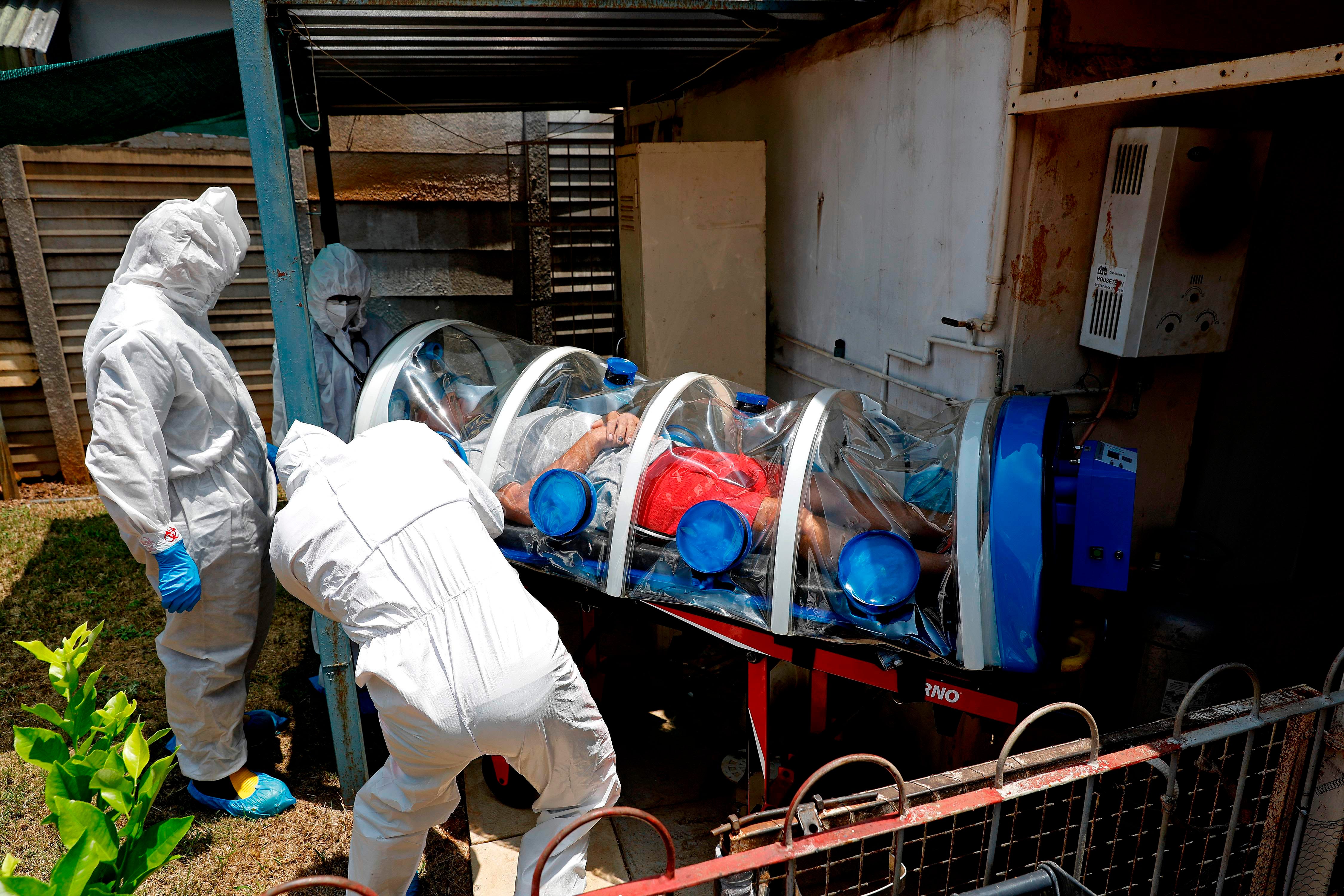 Special Infection Unit paramedics and a doctor load a man showing symptoms of COVID-19 coronavirus into the isolation chamber equipped with a negative pressure filtration system from his home in the north of Pretoria, South Africa, on Jan. 15, 2021.