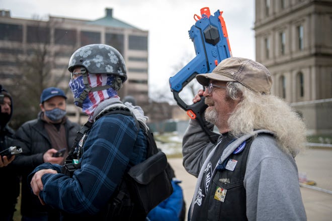 Wayne Koper, 66, of Caro, holds a nerf gun while another man is interviewed by the press outside of the Michigan State Capitol ahead of the anticipated protest in Lansing on Jan. 17, 2021.