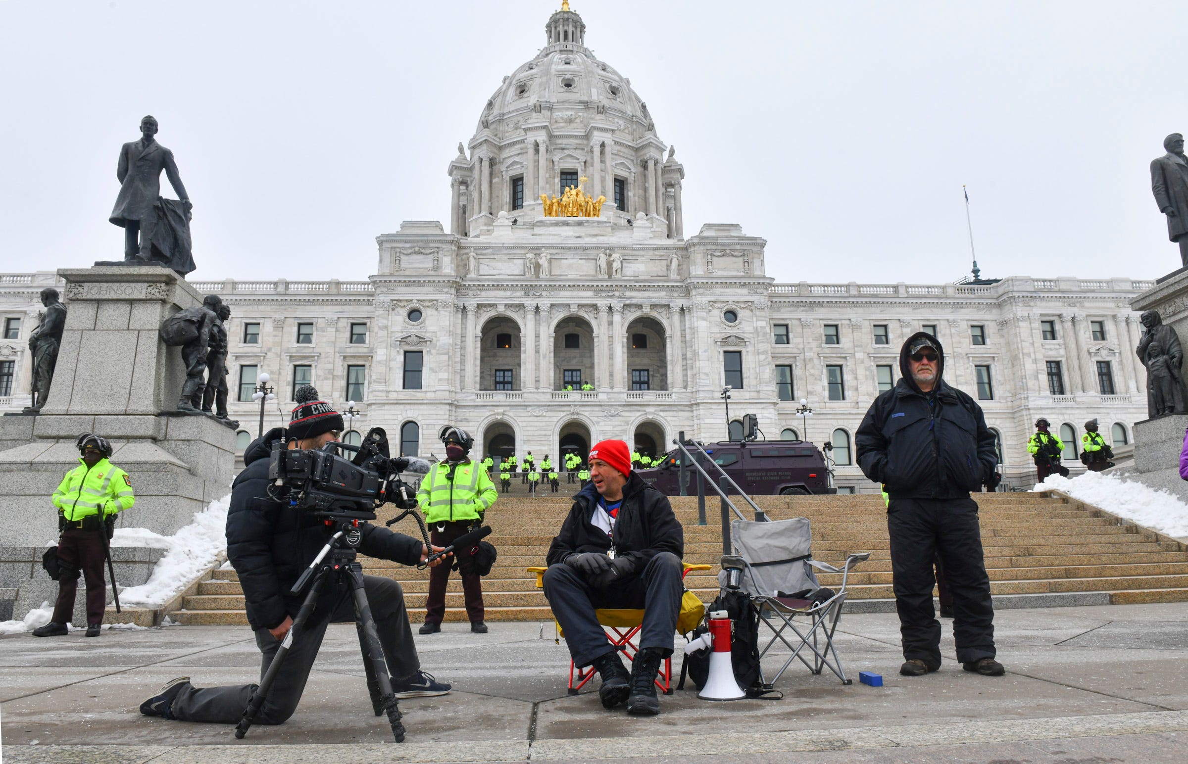 People are interviewed near a line of State Patrol officers Sunday, Jan. 17, 2021, in front of the Minnesota State Capitol in St. Paul.