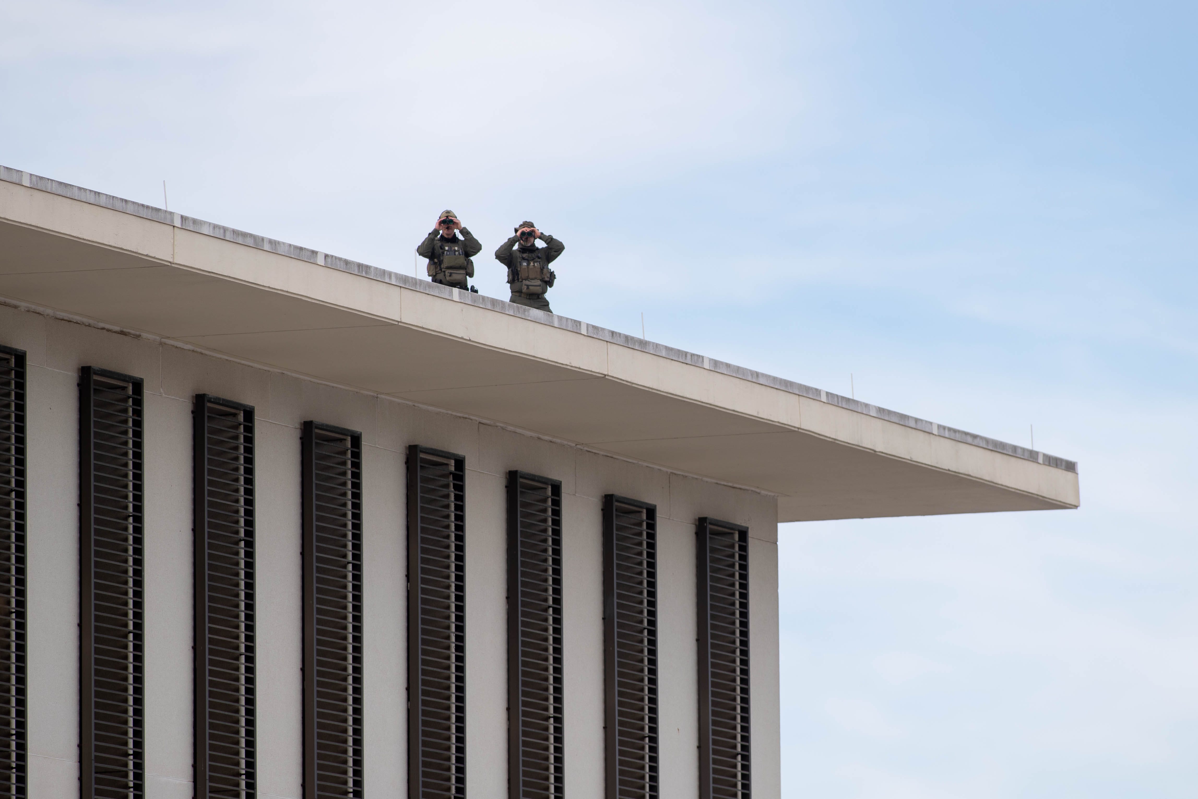 From atop the Florida House of Representatives Office Building in Tallahassee, members of law enforcement use binoculars to survey the area around the Florida Capitol Complex as multiple law enforcement agencies were stationed around the building as a precaution after FBI warnings of potential violence at state capitols on Sunday, Jan. 17, 2021.