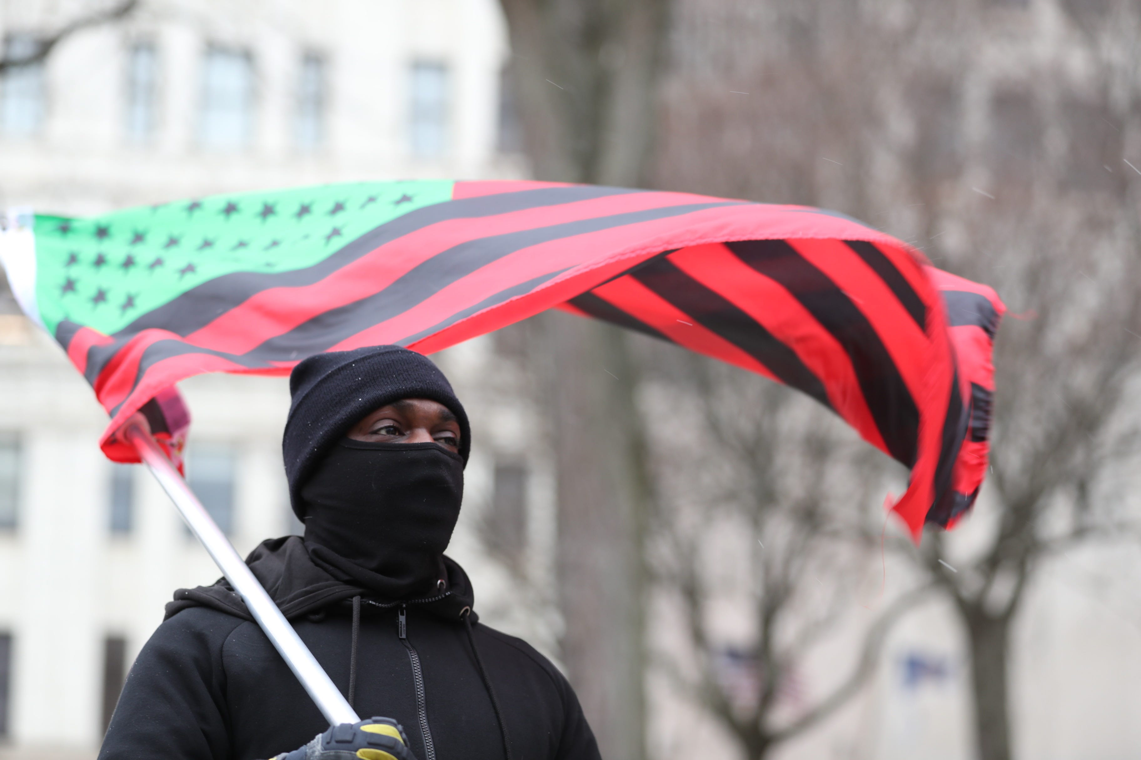 A man carries a Black liberation flag outside the New York state Capitol in Albany on Sunday, Jan. 17, 2021.