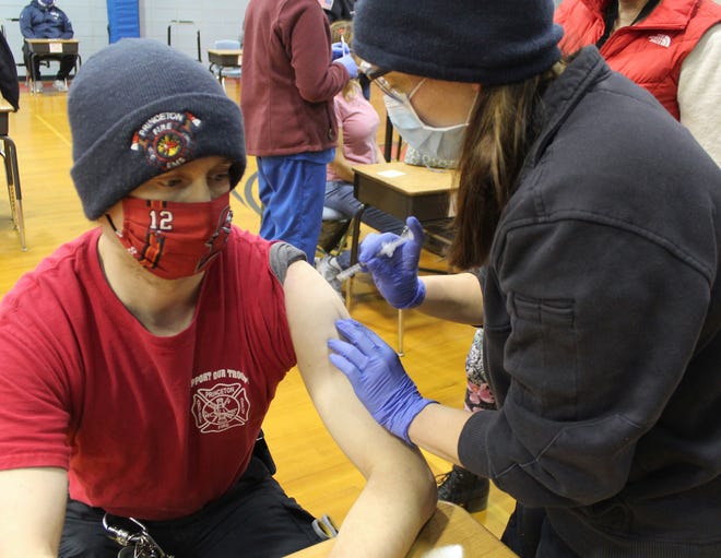 EMT Nicole Melissa Morin, right, administers a COVID-19 vaccine to Princeton Firefighter Brian Henrich in the gym of the Thomas Prince School as Morin and nurse Raquel Hillis moved from person to person.