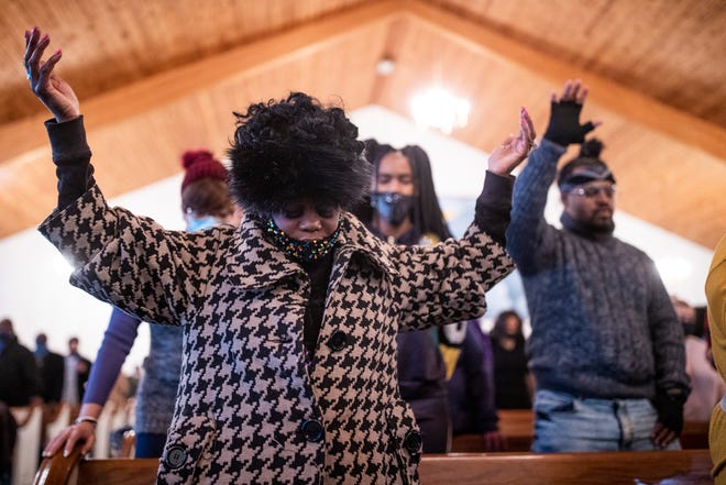 Christina Johnson, left, holds her hands up in prayer during Martin Luther King, Jr. Day services at King Solomon Missionary Baptist Church on Monday. Jan. 18, 2021