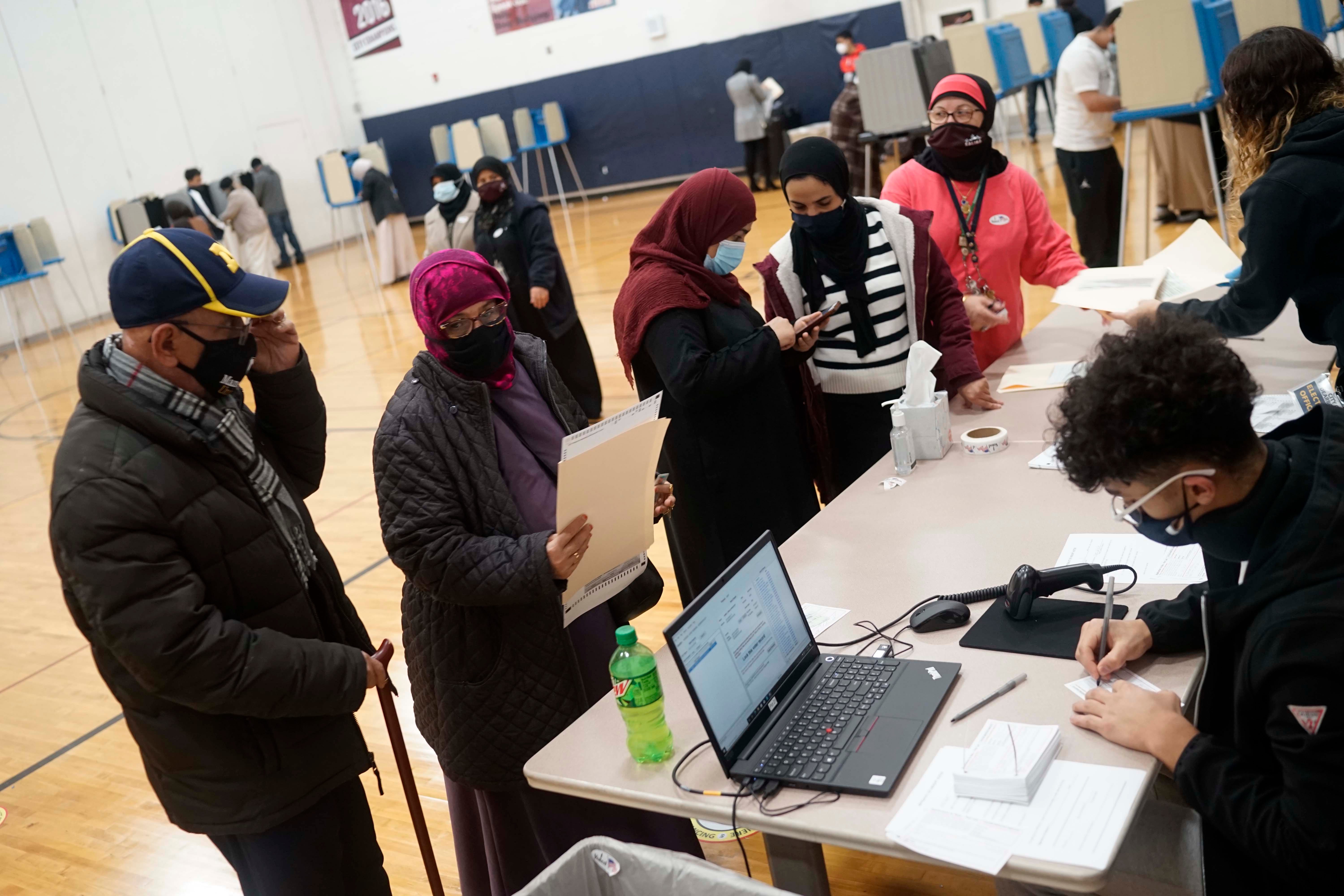 Dawleh Ahmed, left center, and Naji Ahmed, left, wait in line to vote at Salina Elementary School on Nov. 3, 2020, in Dearborn, Mich.