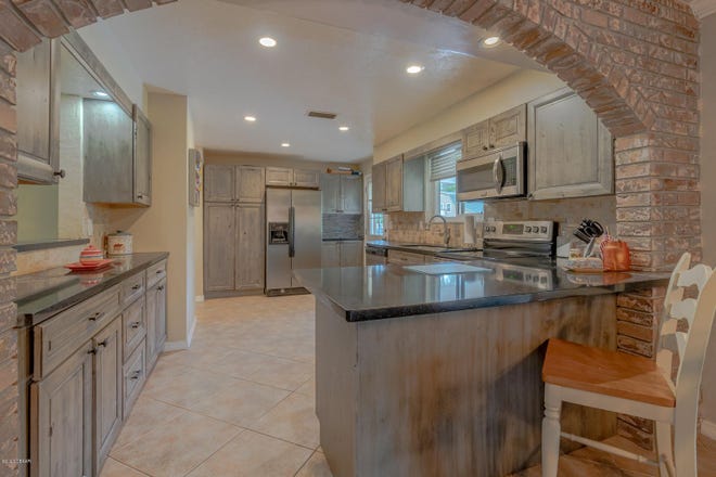 A brick archway leads to this beautifully updated kitchen, featuring new countertops, cabinets and appliances.