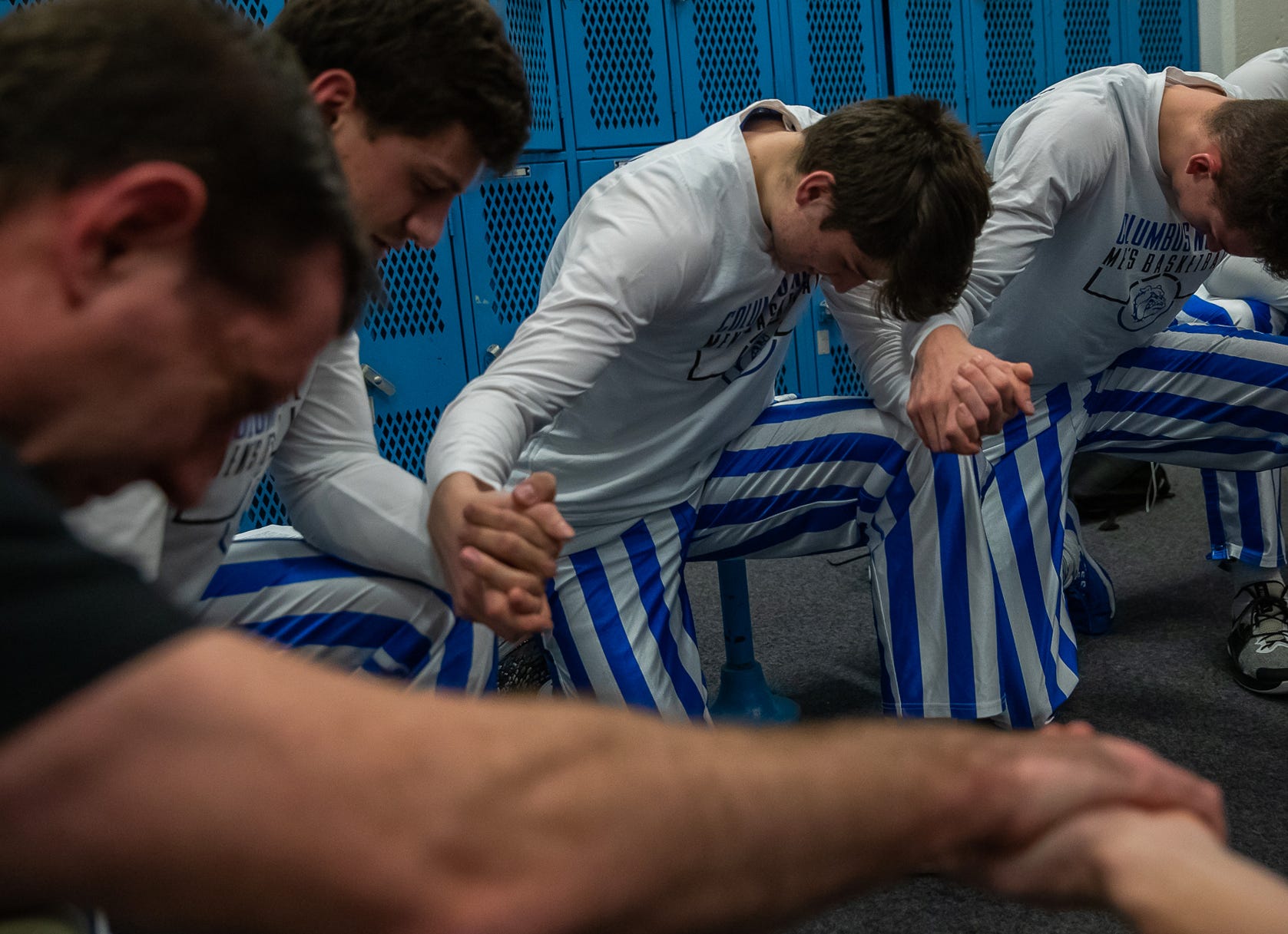 Columbus North head basketball coach Paul Ferguson kneels with his players during a prayer before their home, senior night basketball game against the Seymour Owls at Columbus North High School's Memorial Gymnasium on Tuesday, Feb. 25, 2020.