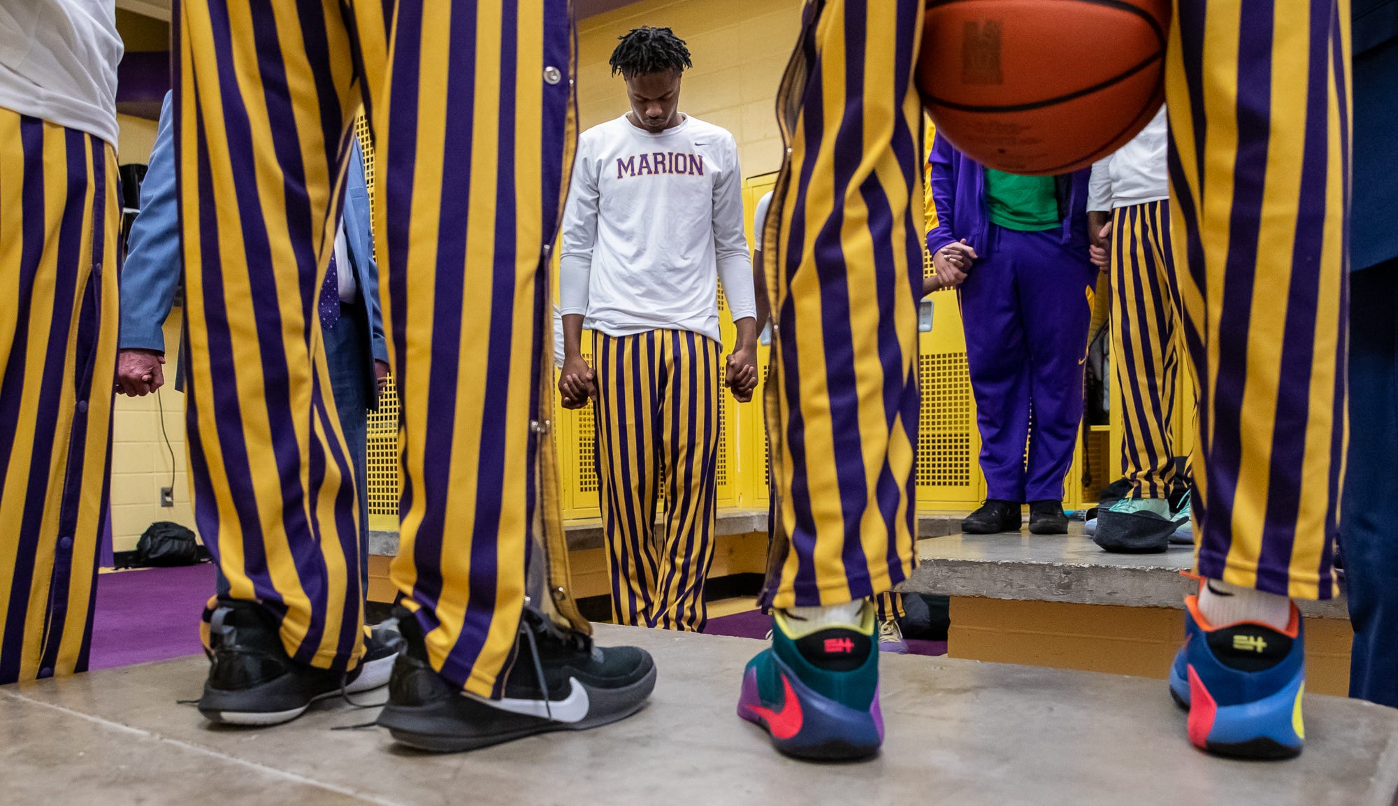 Marion Giants' Brendon Martin says a prayer alongside his teammates and coach inside Marion High School's Bill Green Arena before the teams varsity basketball game against the Fort Wayne Snyder Panthers on Friday, Feb. 28, 2020.