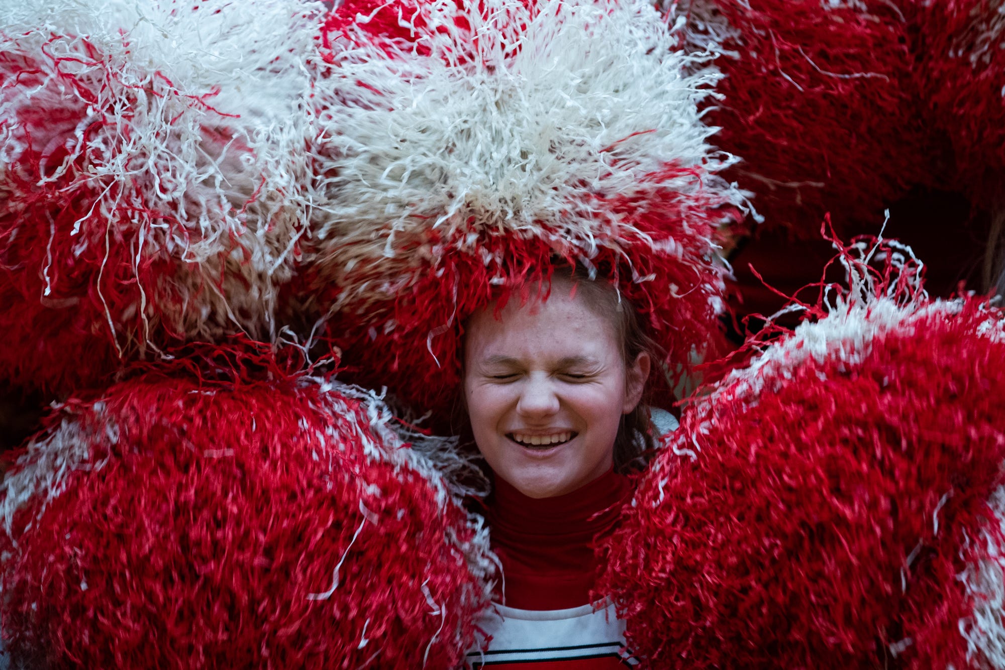 Taylor Mikesell, a freshman cheerleader at Richmond High School, giggles while making pompom letters with the rest of the cheer team before the varsity boys basketball game against the Kokomo Wildkats inside the Tiernan Center gymnasium in Richmond, Ind., on Friday, Feb. 14, 2020.