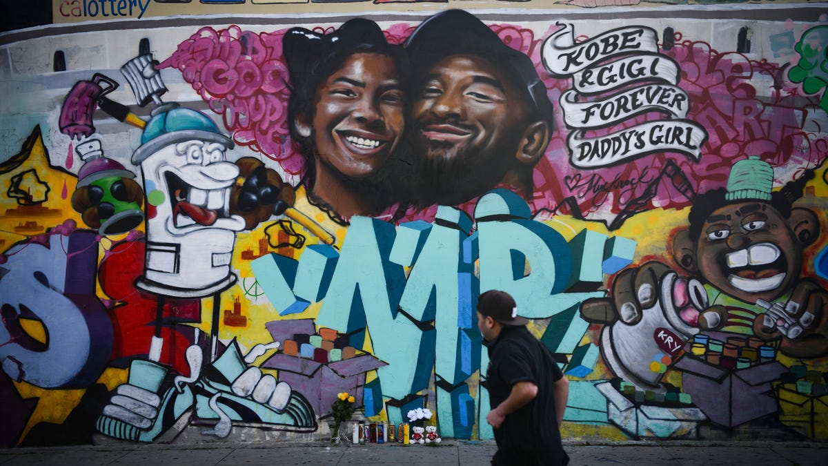 A man walks past a newly painted mural of Kobe Bryant and daughter Gianna Bryant in Los Angeles, Calif., a day after they passed away in a helicopter crash in Los Angeles. 