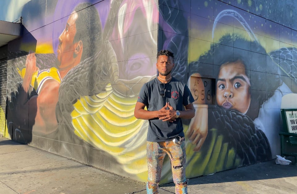 Tehrell Porter stands in front of his mural that will cover three sides of a downtown Los Angeles building.