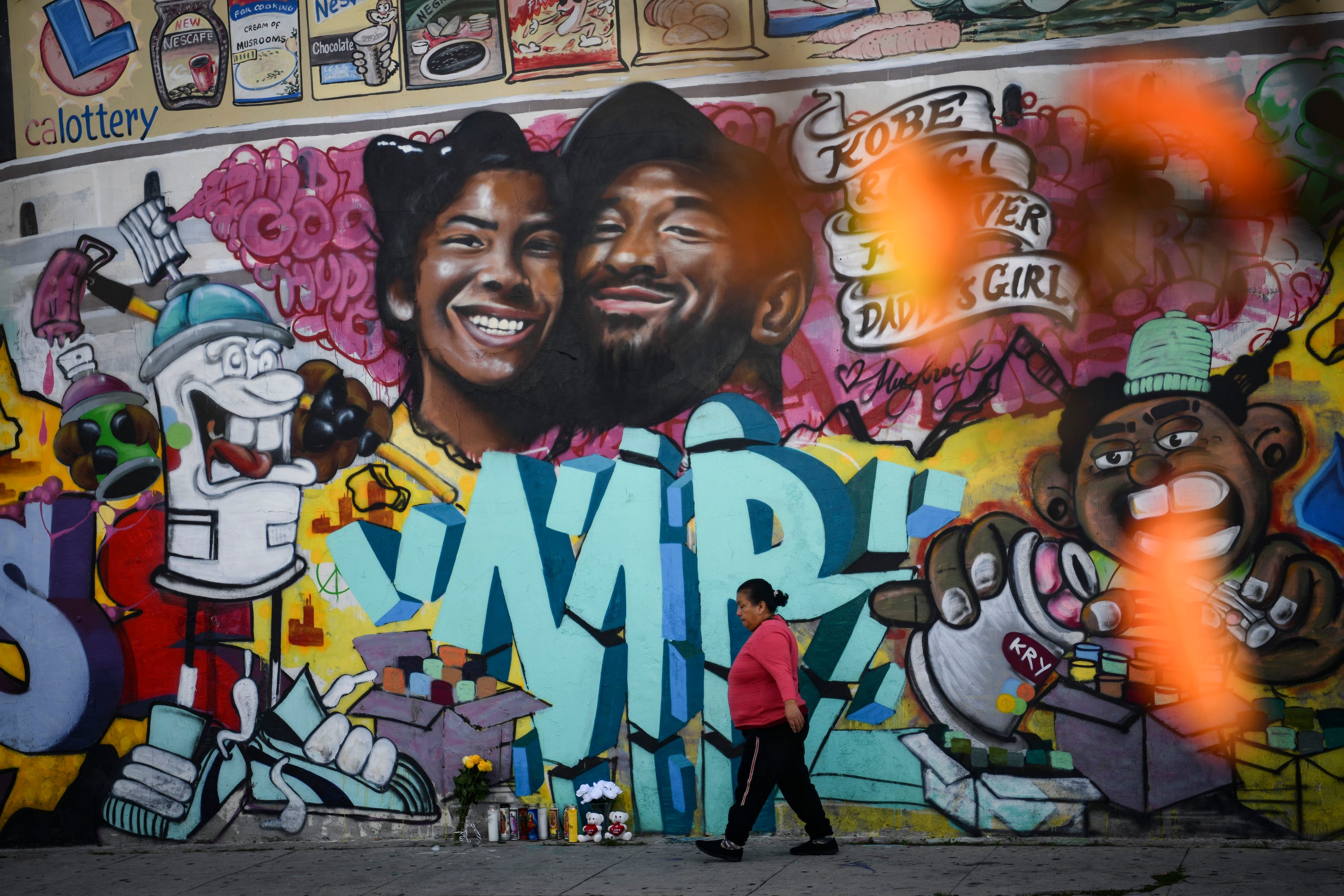 A woman walks past a mural of Kobe Bryant and daughter Gianna Bryant in Los Angeles.