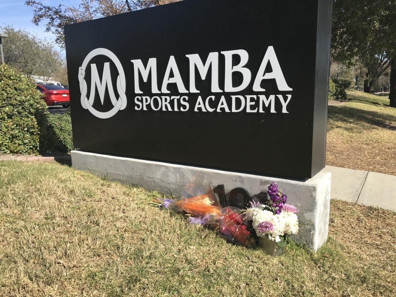 Flowers sit at the base of a Sports Academy sign.