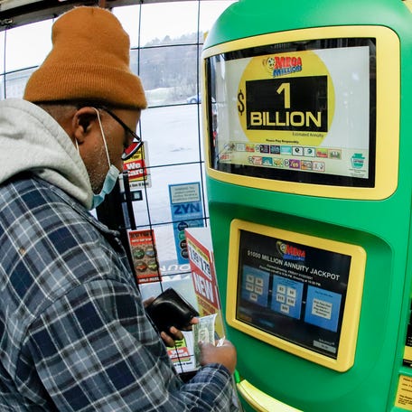 A patron, who did not want to give his name, uses the lottery ticket vending kiosk at a Smoker Friendly store to purchase tickets for the Mega Millions lottery drawing, Friday, Jan. 22, 2021, in Cranberry Township, Pa. The jackpot for the Mega Millions lottery game has grown to $1 billion ahead of Friday night's drawing after more than four months without a winner. (AP Photo/Keith Srakocic) ORG XMIT: PAKS101
