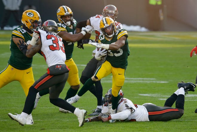 Green Bay Packers' Aaron Jones (33) evades a tackle from Tampa Bay Buccaneers' Lavonte David (54) during the first half of the NFC championship NFL football game in Green Bay, Wis., Sunday, Jan. 24, 2021. (AP Photo/Mike Roemer)