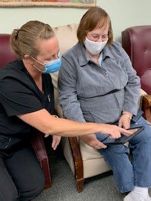 Fort Gratiot Memory Care Services Certified Nurse Aide  April Velez and caregiver Karen Trisch use one of the iPads that are part of a new loan program to help St. Clair County caregivers and patients.