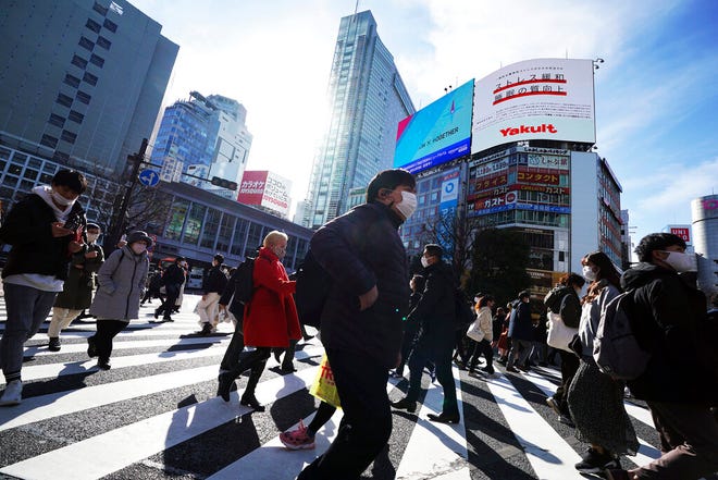 People wearing protective masks to help curb the spread of the coronavirus walk along pedestrian crossings Monday, Jan. 25, 2021 in Tokyo. The Japanese capital confirmed more than 600 new coronavirus cases on Monday. (AP Photo/Eugene Hoshiko)