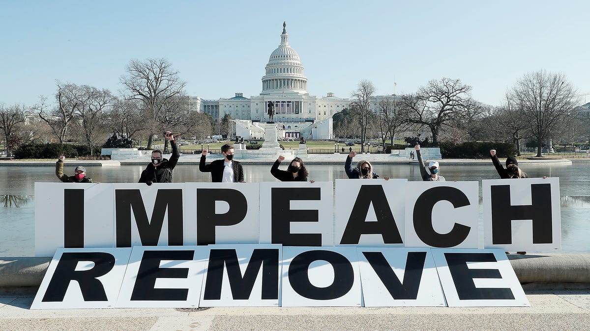 People gather at the base of the U.S. Capitol with large IMPEACH and REMOVE letters on Jan. 12, 2021 in Washington, DC. The group is calling on Congress to impeach and remove President Donald Trump on the day that Democrats introduced articles of impeachment in response to Trump's incitement of a mob entering the U.S. Capitol Building on Jan. 6.