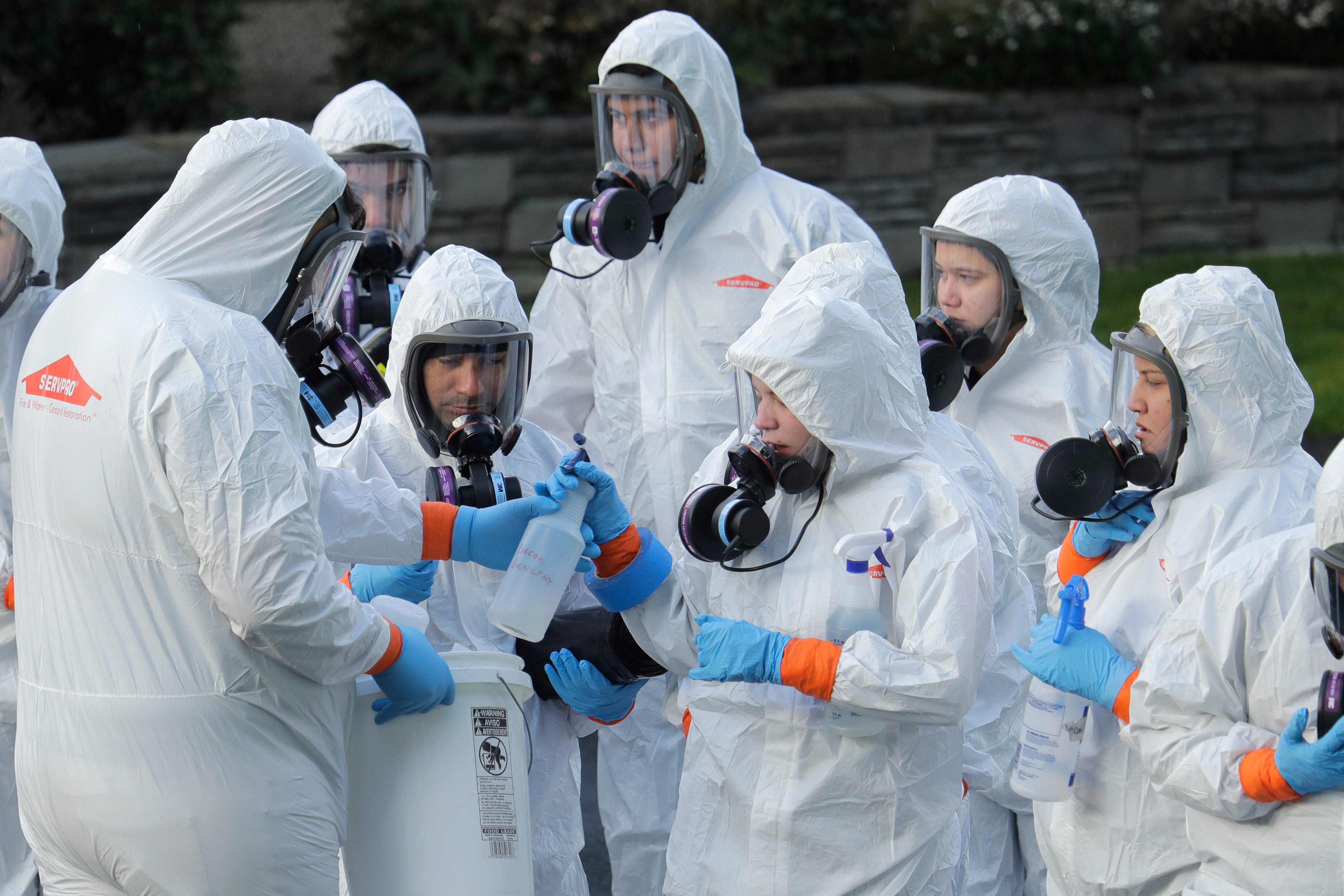 Workers from a disaster recovery team line up before entering the Life Care Center in Kirkland, Wash. to clean and disinfect the facility on March 11, 2020.