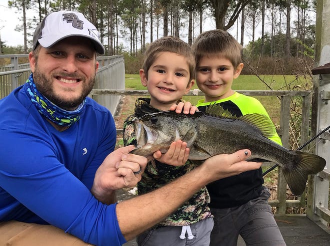 Nathan Smiley, left, shows off a nice largemouth bass he caught with his sons, Owen, 3, center, and Jackson, 5, while fishing at Tenoroc Fish Management Area recently.