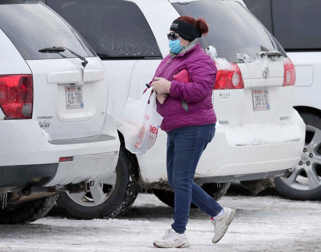 A woman walks in the parking lot wearing a mask at Meijer, Wednesday, January 27, 2021, in Sheboygan, Wis.
