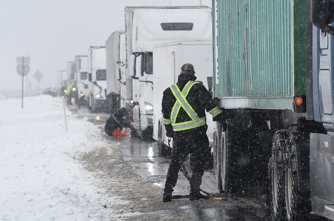 Truck drivers pull over on the west bound I-80 just outside of Reno, Nev. to install chains on their semi-trailer trucks on Jan. 28, 2021.