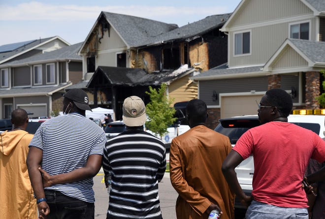 FILE - In this Aug. 5, 2020, file photo, people look at a house where five people were found dead after a fire in Denver. Three teenagers have been arrested in connection with the fire that killed five recent immigrants, including two children, from the West African nation of Senegal, police said Wednesday, Jan. 27, 2021.