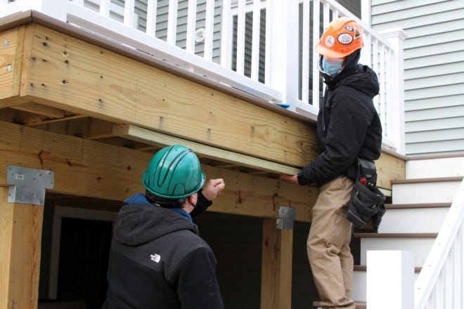 Blue Hills students Jonathan McGettrick and Jake Geaney work on the back deck of a Canton home.