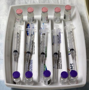 FILE — Syringes and vials of the Pfizer COVID-19 vaccine sit in a try prior to the start of the Peninsula Community Health Services COVID-19 vaccination clinic at the Gateway Center in Bremerton in January.