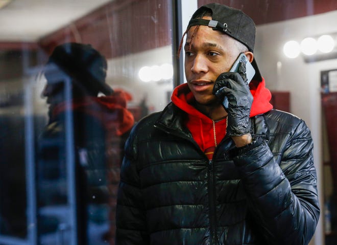Charles Crawford parle au téléphone tout en coupant les cheveux au Campus Barber Shop le samedi 30 janvier 2021.