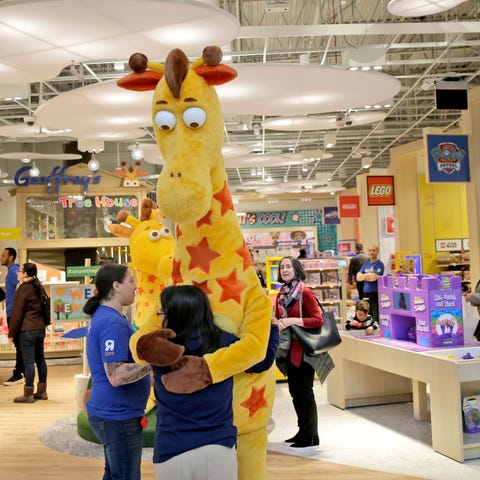 A girl hugs the Toys R Us mascot, Geoffrey, at the